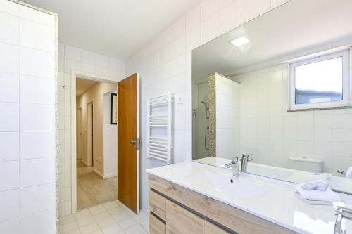 a bathroom with a sink and a tub and a mirror at Apartamento familiar no centro histórico - Afonso Henriques in Braga