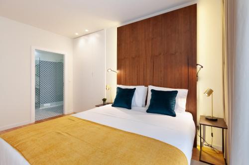 um quarto com uma grande cama branca com almofadas azuis em Sé Apartamentos - Avenida Residence em Braga