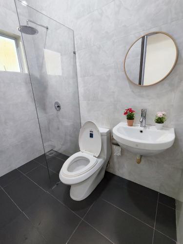 a bathroom with a toilet and a sink and a mirror at Ipoh Lake View Cozy Home Big House in Lahat