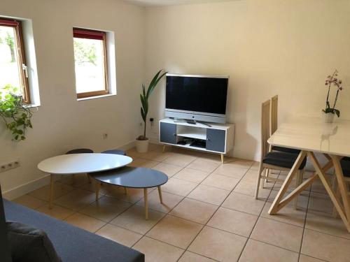 a living room with a flat screen tv and a table at La Mouette Rose - a zen guest-house in Lauterbourg 