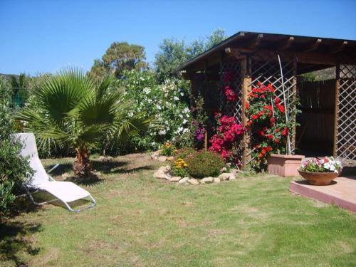 einen Garten mit einem weißen Stuhl im Gras in der Unterkunft Casetta Marieoria Chia in Chia