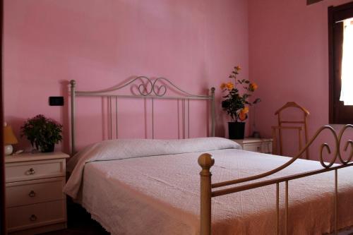 een slaapkamer met roze muren en een bed met witte lakens bij Casetta Marieoria Chia in Chia