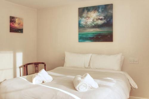 Una cama blanca con dos toallas blancas. en Fisherman's Cottage, en Cockenzie