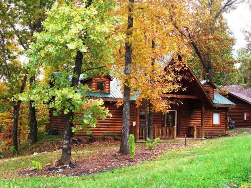 a log cabin surrounded by trees and green grass at Three Bear Lodge in Ridgedale