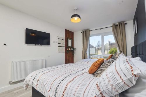 a bedroom with a bed with a television on the wall at Homebird Property - Ash Tree House in Leeds