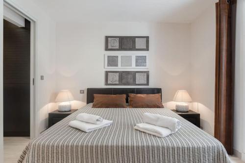 una camera da letto con un grande letto con due cuscini sopra di Paradis en Rez de jardin - Standing - Vue Mer - piscine privée a Vallauris