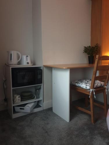 a kitchen with a desk with a tv and a chair at Sweet Dreams in Luton