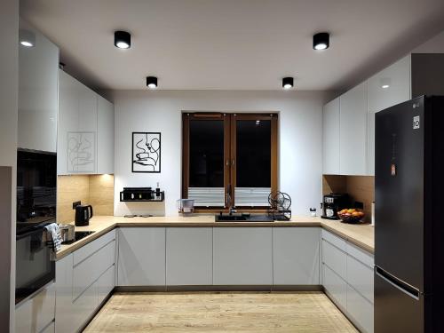 a kitchen with white cabinets and a black refrigerator at Dom Przy Lesie na Warmii in Woryty