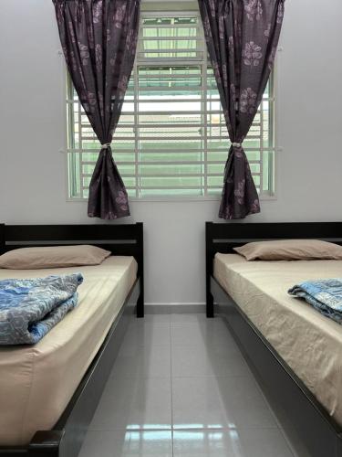two beds in a room with a window at Suri Kayangan in Arau
