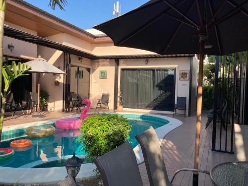 uma piscina com um guarda-sol ao lado de uma casa em Barbé La Maison em Hua Hin