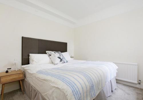 ロンドンにあるFabulous Hyde Park Mews Apartment London w2 MEWSのベッドルーム1室(大型ベッド1台、木製ヘッドボード付)