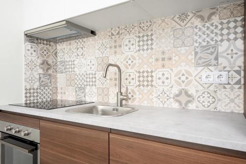 a kitchen with a sink and a tiled wall at Sé Apartamentos - Casa Do Raio Center Apartments in Braga