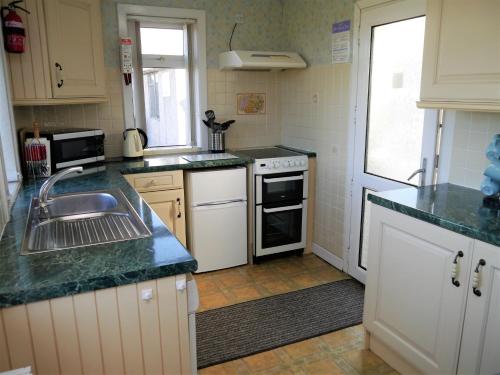 a kitchen with a sink and a stove top oven at Woodhall Cottage in Annan