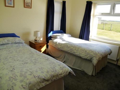 two beds in a bedroom with a window at Woodhall Cottage in Annan