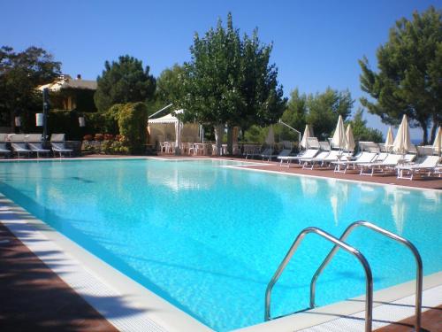 ein großer blauer Pool mit Stühlen und Sonnenschirmen in der Unterkunft Fonteluna Residence in Centola