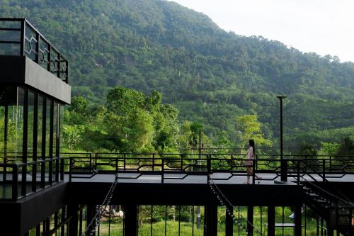 a woman walking on a bridge in front of a mountain at D’Endless Resotel in Baen