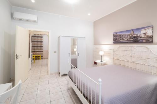 シラクーサにあるSyracuseApartments IL PIAVE di SIRACUSA Appartamento per 6 persone vicino ad ORTIGIA a 200m dal MAREの白いベッドルーム(大型ベッド1台付)、廊下が備わります。