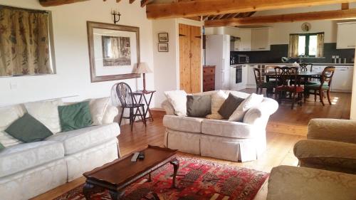 a living room with two white couches and a table at Duleep Singh Barn in Botesdale