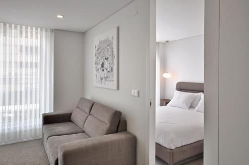 um quarto com uma cama, um sofá e uma cadeira em Sé Apartamentos - Luxury Apartment em Braga