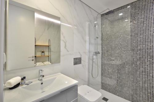 uma casa de banho branca com um lavatório e um chuveiro em Sé Apartamentos - Luxury Apartment em Braga