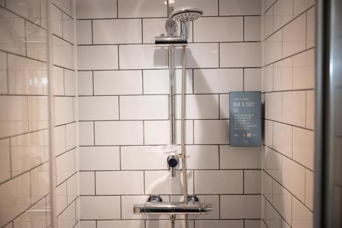 a shower in a bathroom with white tiles at Ardencaple Hotel by Greene King Inns in Rhu