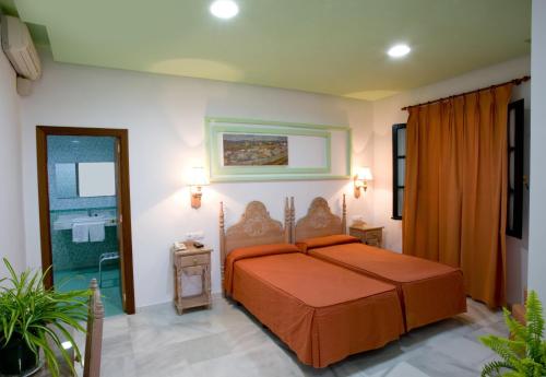 1 dormitorio con 1 cama con colcha de color naranja en Los Helechos, en Sanlúcar de Barrameda