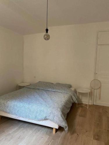a white bedroom with a bed and two tables at Appartement de charme au cœur du centre ville . in Millau