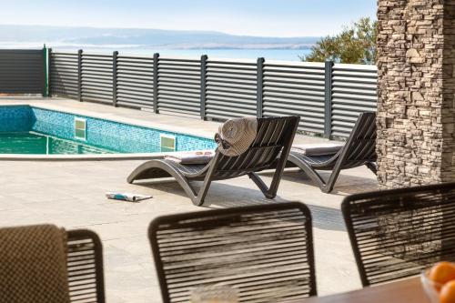 two chairs and a table next to a swimming pool at Villa Chanel in Crikvenica