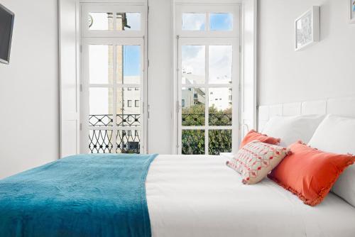 a white bedroom with a bed with orange and blue pillows at Porta 34 Apartments in Braga