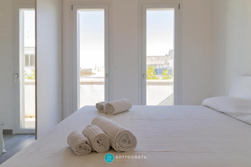 a bedroom with a bed with rolled towels on it at MADREPERLA - SAN FOCA in San Foca