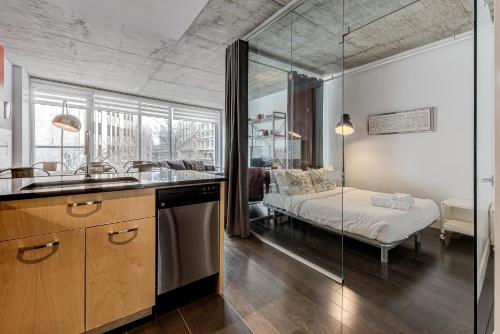 a kitchen with a sink and a bedroom with a bed at Les Immeubles Charlevoix - Le 760-209 in Quebec City
