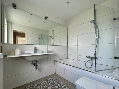 ein Bad mit einem Waschbecken, einer Dusche und einem WC in der Unterkunft Jaardenhuug - EG in Utersum