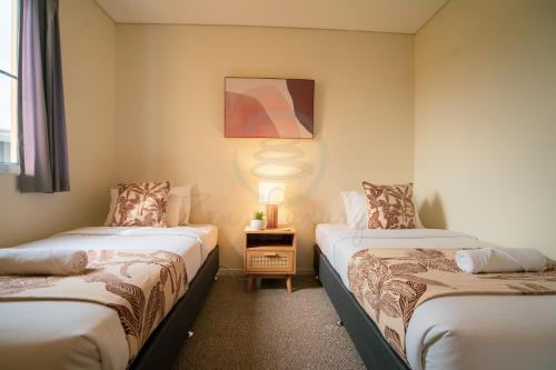 a room with two beds and a table with a lamp at ZEN PARADISE - 2-BR Waterfront Ocean View Retreat in Darwin