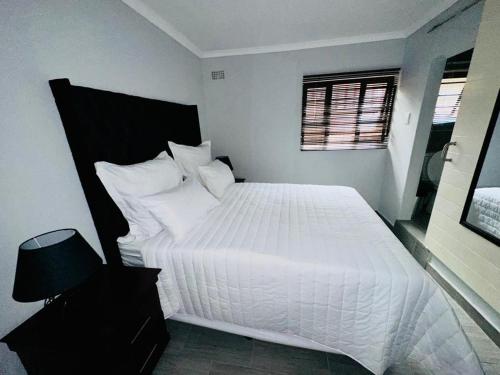 una camera da letto con un grande letto bianco e una finestra di The Curve Apartments Unit 5 a Johannesburg