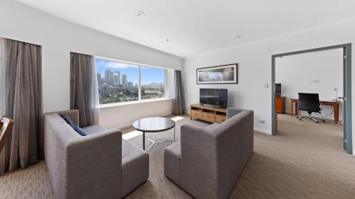 a living room with two chairs and a large window at Holiday Inn Sydney Potts Point in Sydney