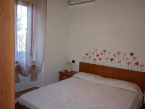 a bedroom with a bed and a window with flowers on the wall at Appartamenti Piombino Isola d'Elba in Rio Marina