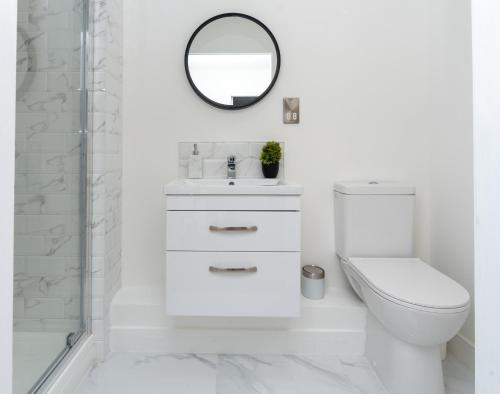 a white bathroom with a toilet and a mirror at Bishops Lynn House Apartments - Town Centre in King's Lynn