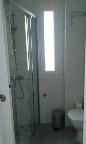 a bathroom with a shower and a toilet and a window at CASA BALUARTE in Conil de la Frontera