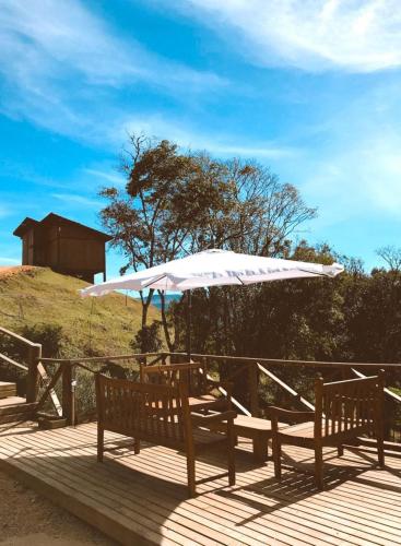 a table with a white umbrella on a deck at Cabanas Recanto do Rancho - Rancho Queimado in Rancho Queimado
