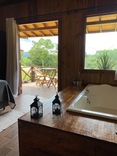 a bedroom with a tub and a bed and a window at Cabanas Recanto do Rancho - Rancho Queimado in Rancho Queimado