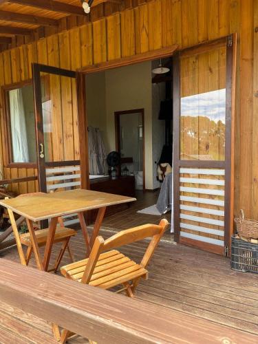 a wooden table and chairs on the porch of a cabin at Cabanas Recanto do Rancho - Rancho Queimado in Rancho Queimado