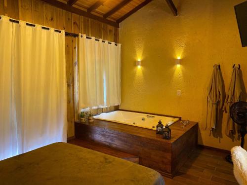 a bathroom with a bath tub and a bed and a tub at Cabanas Recanto do Rancho - Rancho Queimado in Rancho Queimado