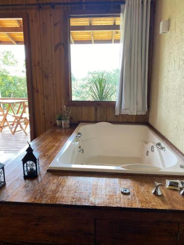 a large bath tub in a room with a window at Cabanas Recanto do Rancho - Rancho Queimado in Rancho Queimado
