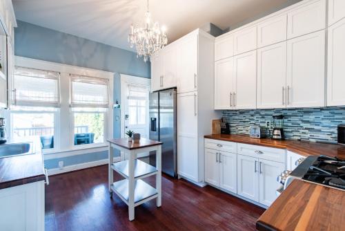 a kitchen with white cabinets and a chandelier at Luxe Highlands Home! King BR~Fire Pit~Yard Games in Louisville