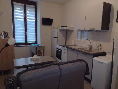 a kitchen with a couch and a table in a room at Appartement RDC chez Caroline in Bourbonne-les-Bains