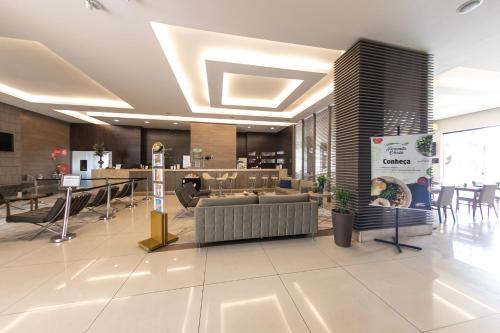 a lobby with a couch and chairs in a building at Class Hotel Guaxupé in Guaxupé