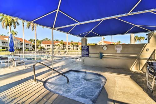 a hot tub on a deck with a blue umbrella at St Pete Condo with Private Lanai and Community Pool! in St Petersburg