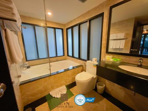 a bathroom with a tub and a toilet and a sink at C & N Resort and Spa - SHA Extra Plus in Patong Beach