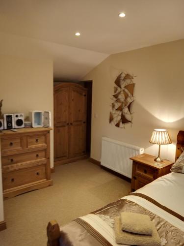 a bedroom with a bed and a dresser with a lamp at Deuglawdd in Pwllheli