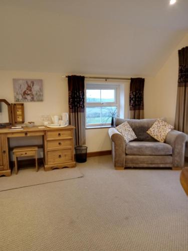 a living room with a couch and a desk and a window at Deuglawdd in Pwllheli